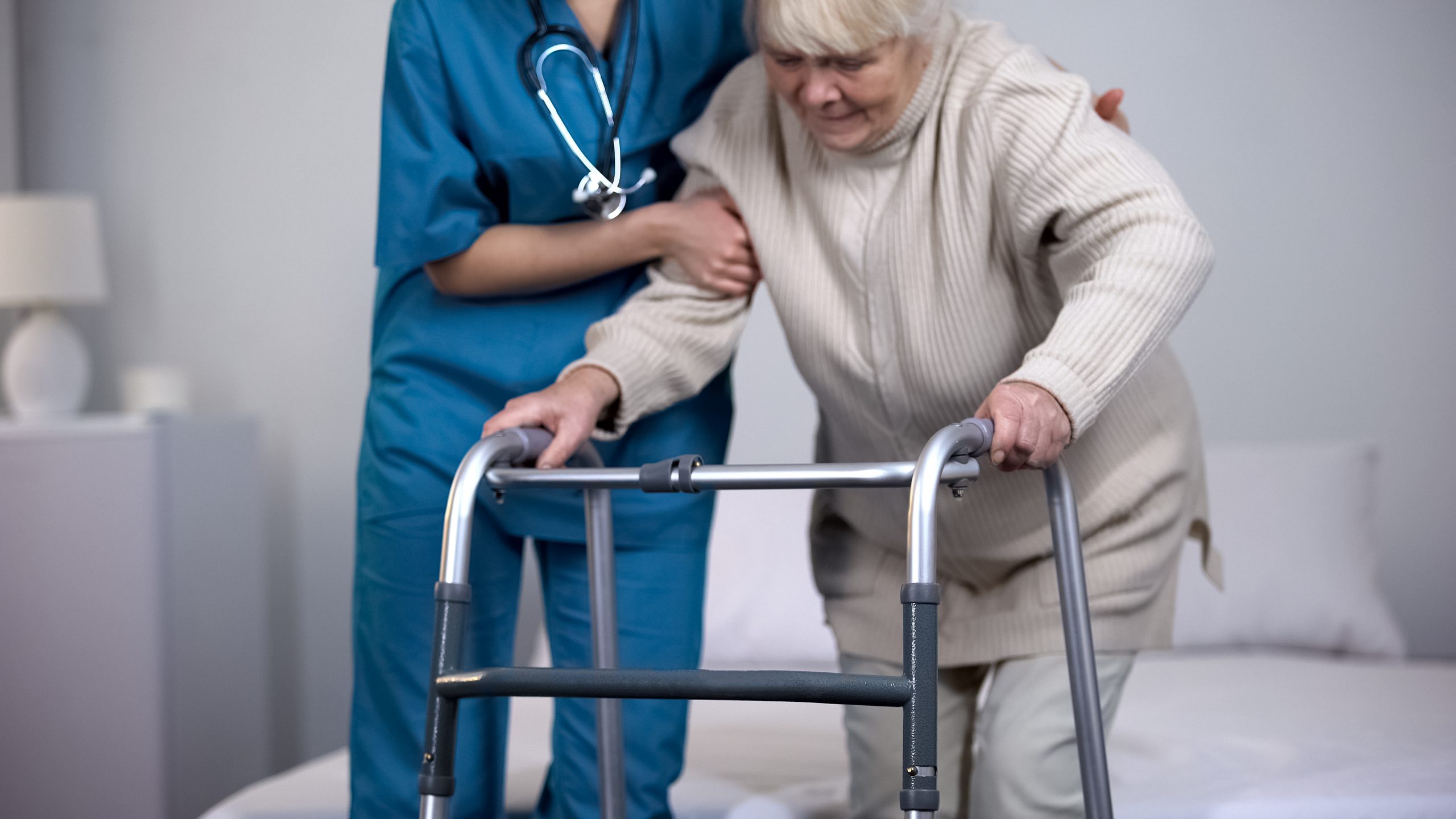 Nurse assisting patient walking frame, hip joint replacement rehabilitation